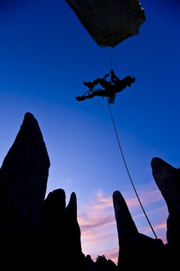 Climber dangling from a rope. clipart