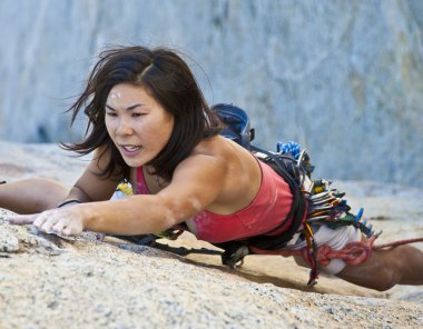 Female climber clinging to a cliff. clipart
