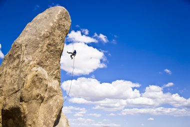 Rock climber rappelling. clipart