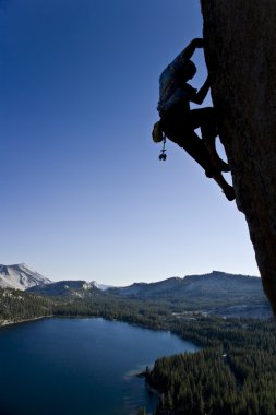 Rock climber clinging to a cliff. clipart