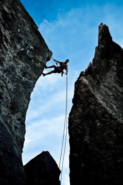 Rock climber rappelling. clipart