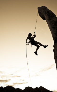 Rock climber rappelling. clipart