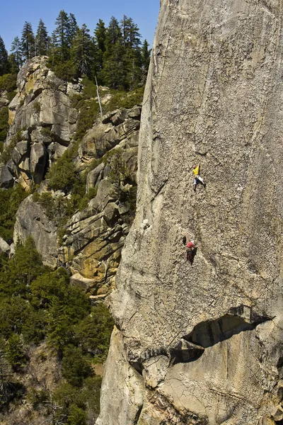 Tema van klimmers oplopende een steile rotswand — Stockfoto