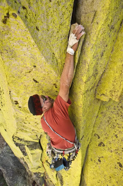 Male climber working his way up a steep crack.