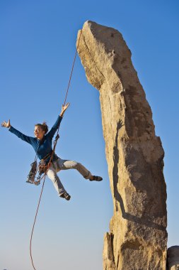 Female rock climber rappelling. clipart