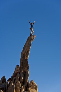 Female rock climber reaching the summit. clipart