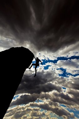 Climber clinging to a cliff. clipart