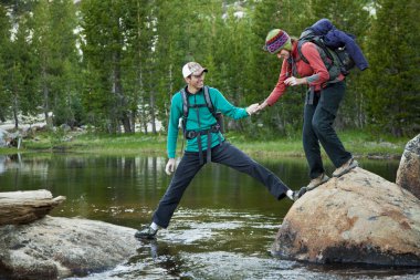 Hikers crossing a stream. clipart