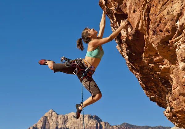 Vrouwelijke rock klimmer klampt zich vast aan een klif. — Stockfoto