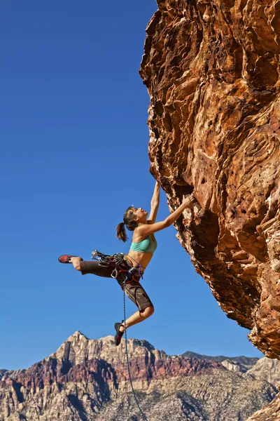 Vrouwelijke rock klimmer klampt zich vast aan een klif. — Stockfoto