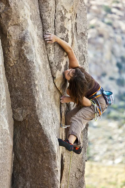 Female climber clinging to a cliff. Royalty Free Stock Images
