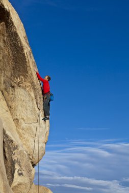 Climber clinging to a cliff. clipart