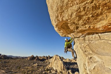 Rock climber clinging to a cliff. clipart