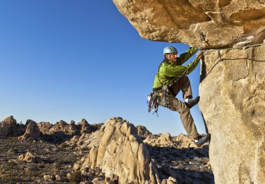 Rock climber clinging to a cliff. clipart