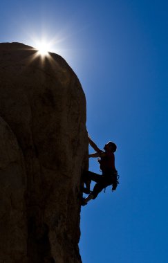 Rock climber clinging to a cliff. clipart