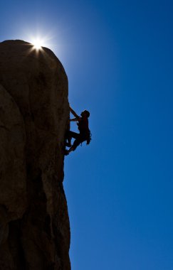 Rock climber clinging to a cliff. clipart