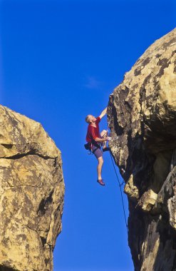 Climber clinging to a cliff. clipart