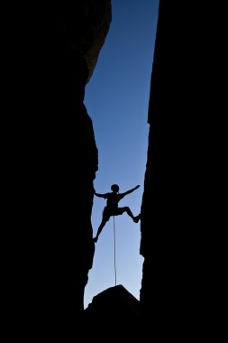 Rock climber clinging to a cliff. clipart