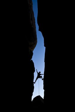 Rock climber clinging to a cliff. clipart