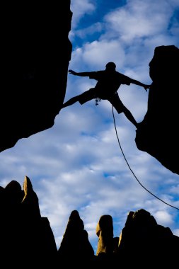 Rock climber reaching across a gap. clipart