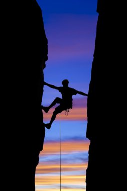Rock climber reaching across a gap.