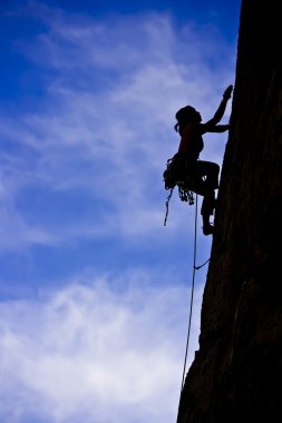 Rock climber clinging to a cliff. clipart