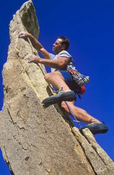 Bergsteiger klammert sich an eine Klippe. — Stockfoto