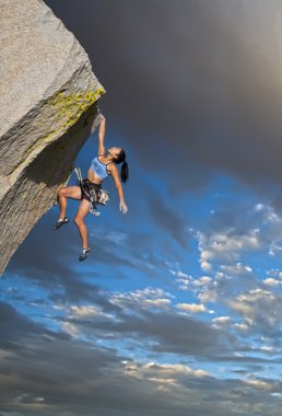 Rock climber clinging to a cliff. clipart