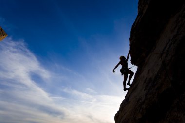 Rock climber clinging to a cliff. clipart