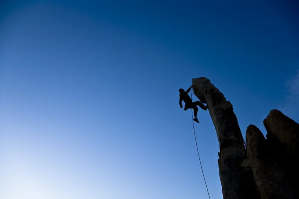 Bergsteiger, der von einer Spitze baumelt. — Stockfoto