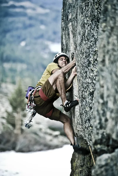 Rock klimmer klampt zich vast aan een klif. — Stockfoto