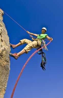 Rock climber rappelling. clipart