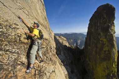 Rock climber clinging to a cliff. clipart