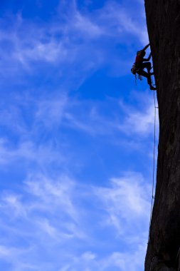 Rock climber clinging to a cliff. clipart