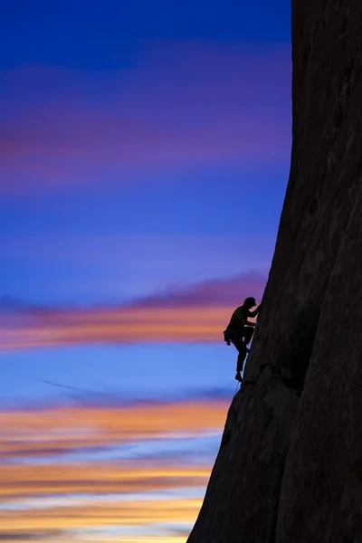 Rock klimmer klampt zich vast aan een klif. — Stockfoto