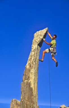 Rock climber dangles from the edge. clipart