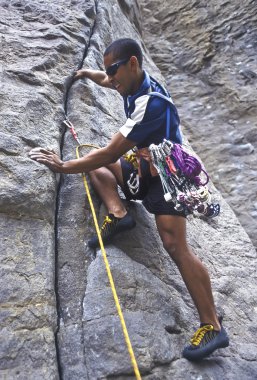 Rock climber clinging to a cliff. clipart