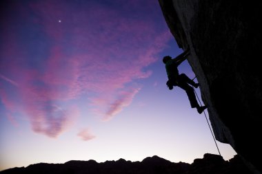 Rock climber clinging to an overhang. clipart