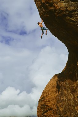 Rock climber clinging to a cliff. clipart