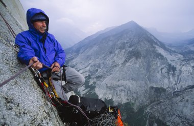 Rock climber and approaching storm. clipart