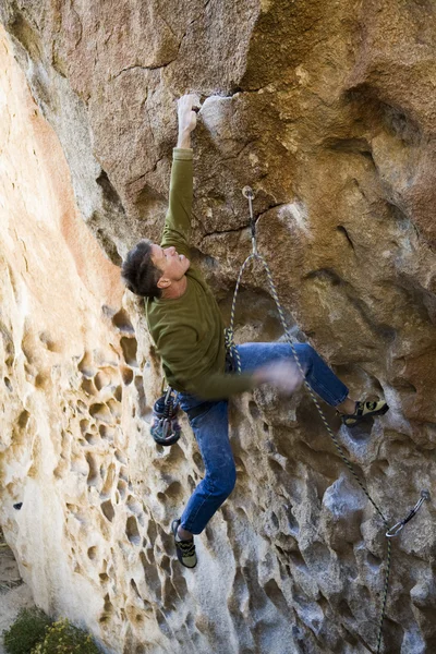 Bergsteiger klammert sich an eine Klippe. — Stockfoto