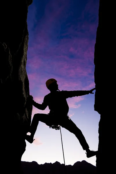 Rock klimmer bereiken over een kloof. — Stockfoto