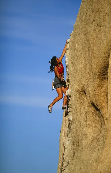 女性のクライマーが崖にしがみついています。. — ストック写真
