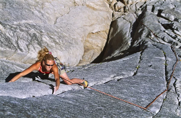 Vrouwelijke klimmer klampt zich vast aan een klif. — Stockfoto
