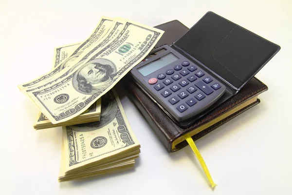 Dollar, anteckningsbok och miniräknare Stockbild