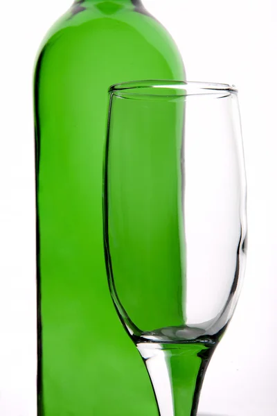 Transparentes Glas auf einem Hintergrund aus grünen Flaschen — Stockfoto