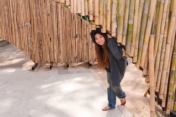 Giovane donna si piega sotto arco di bambù e sorride — Foto Stock