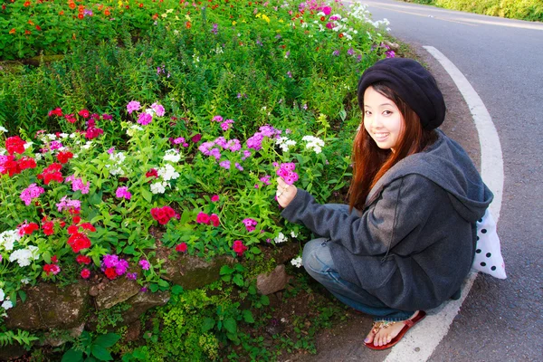 Jonge vrouw plukken bloemen en glimlach — Stockfoto