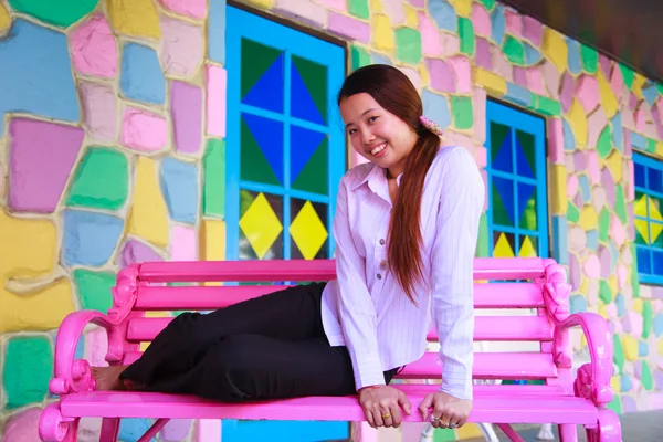Aziatische jonge vrouwen zitten op roze stoel — Stockfoto
