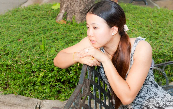 Asian women distracted on bench in park — Stock Photo, Image